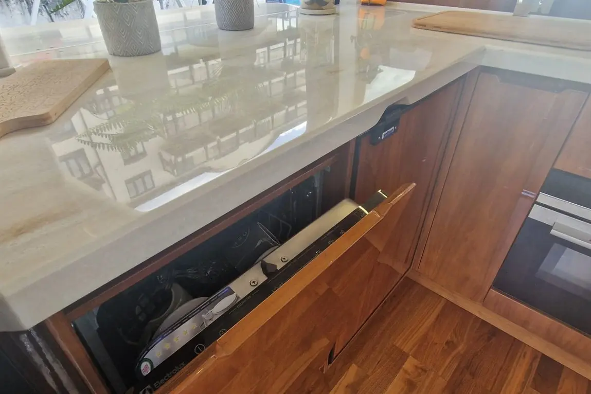 Modern kitchen featuring a sleek countertop, wooden cabinetry, and a partially open drawer revealing kitchen appliances.